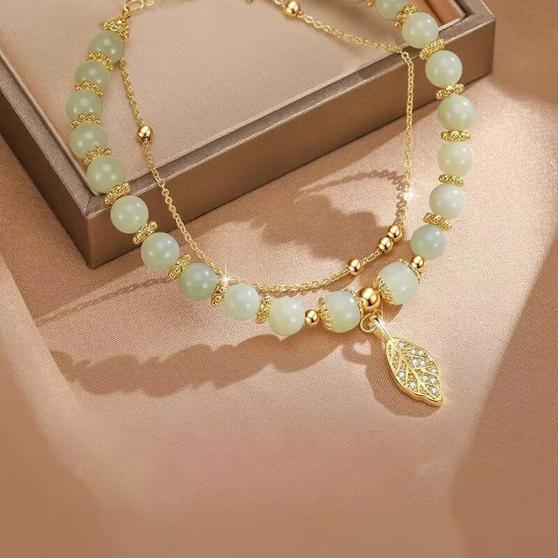 กำไลหยกสีเขียวสไตล์จีนปี 2026 สำหรับผู้หญิง ประดับด้วยใบไม้สีทองสวยงาม สายรัดข้อมือแบบกำไลสองชั้น ของขวัญสำหรับสาวๆ