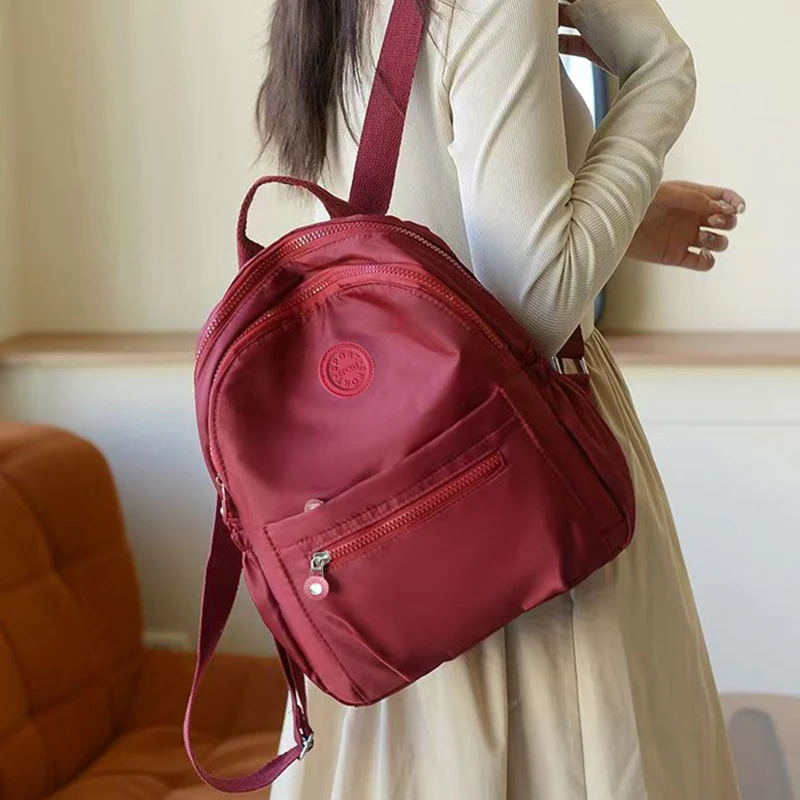 Neutral Style Backpack for Men and Women, Suitable for Travel and Photography Made of Nylon Material, with a Round Logo Design.