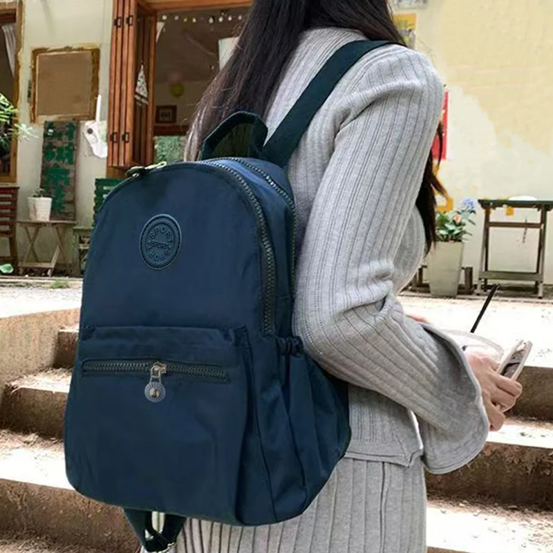 Neutral Style Backpack for Men and Women, Suitable for Travel and Photography Made of Nylon Material, with a Round Logo Design.
