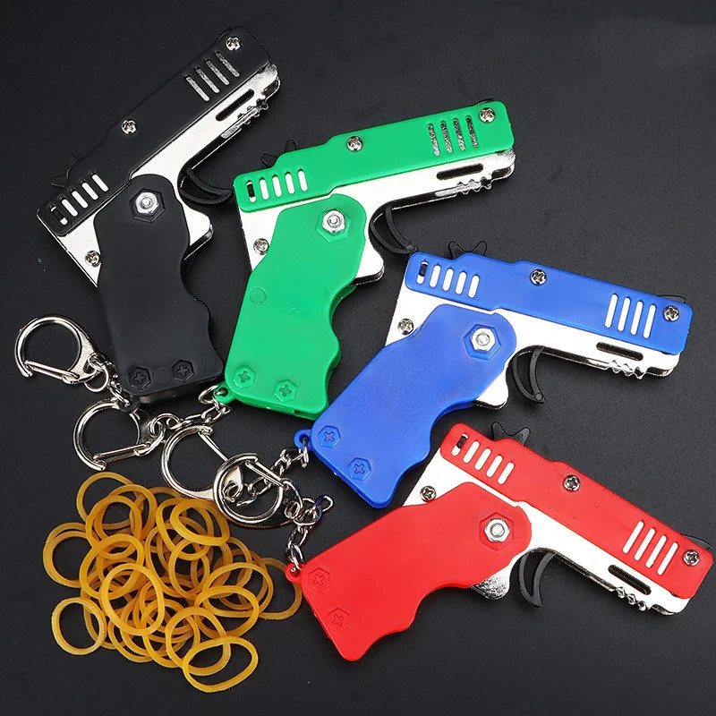 1 Uds Mini pistola de Metal banda de goma plegable juguete llavero para deportes al aire libre juguete 6 ráfagas pistola de goma regalos para niños juguetes de pistola de recuerdo de fiesta