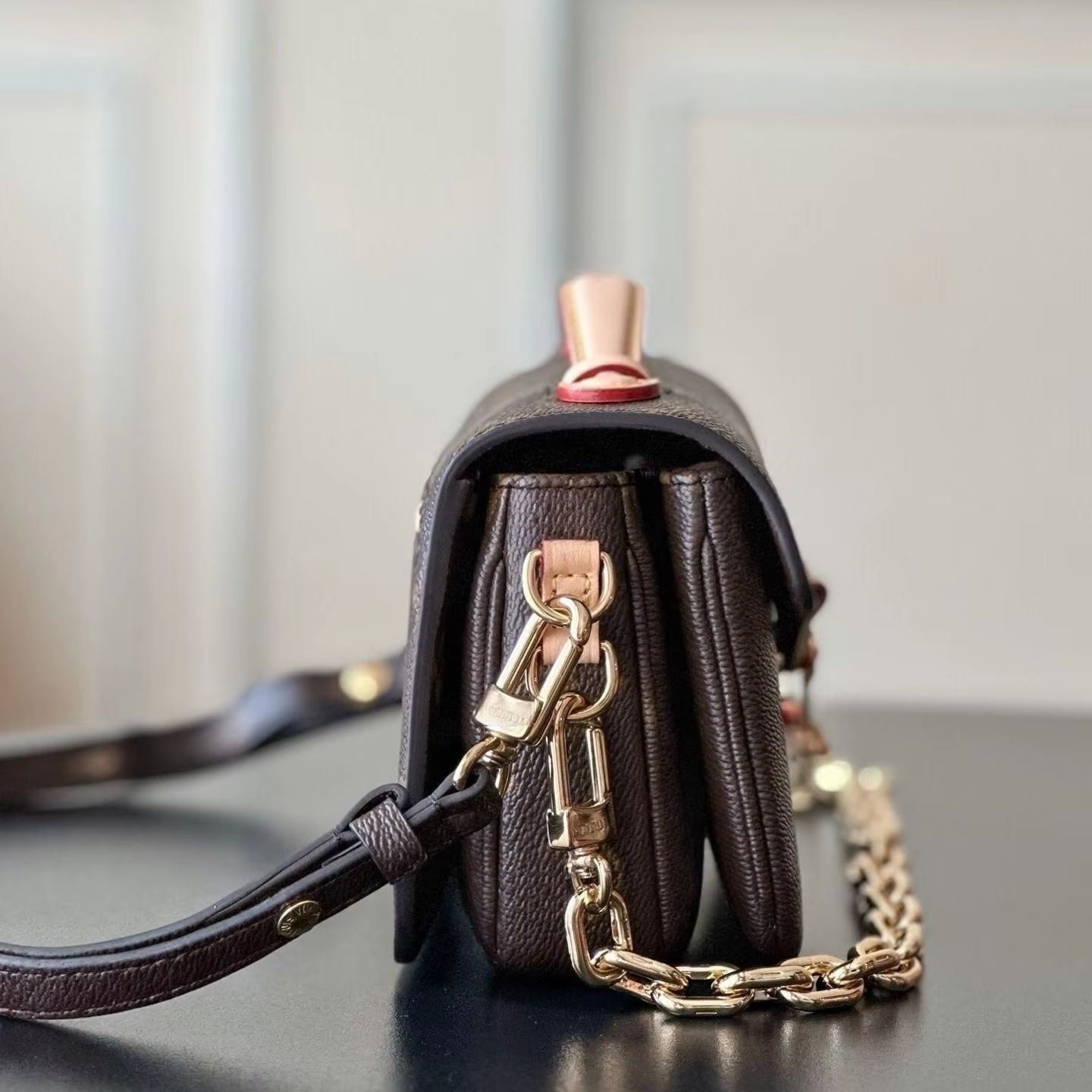 Ciemnobrązowa torebka crossbody z klapką z tłustej skóry, skórzany uchwyt górny, okucia z zamkiem w kolorze starego złota.