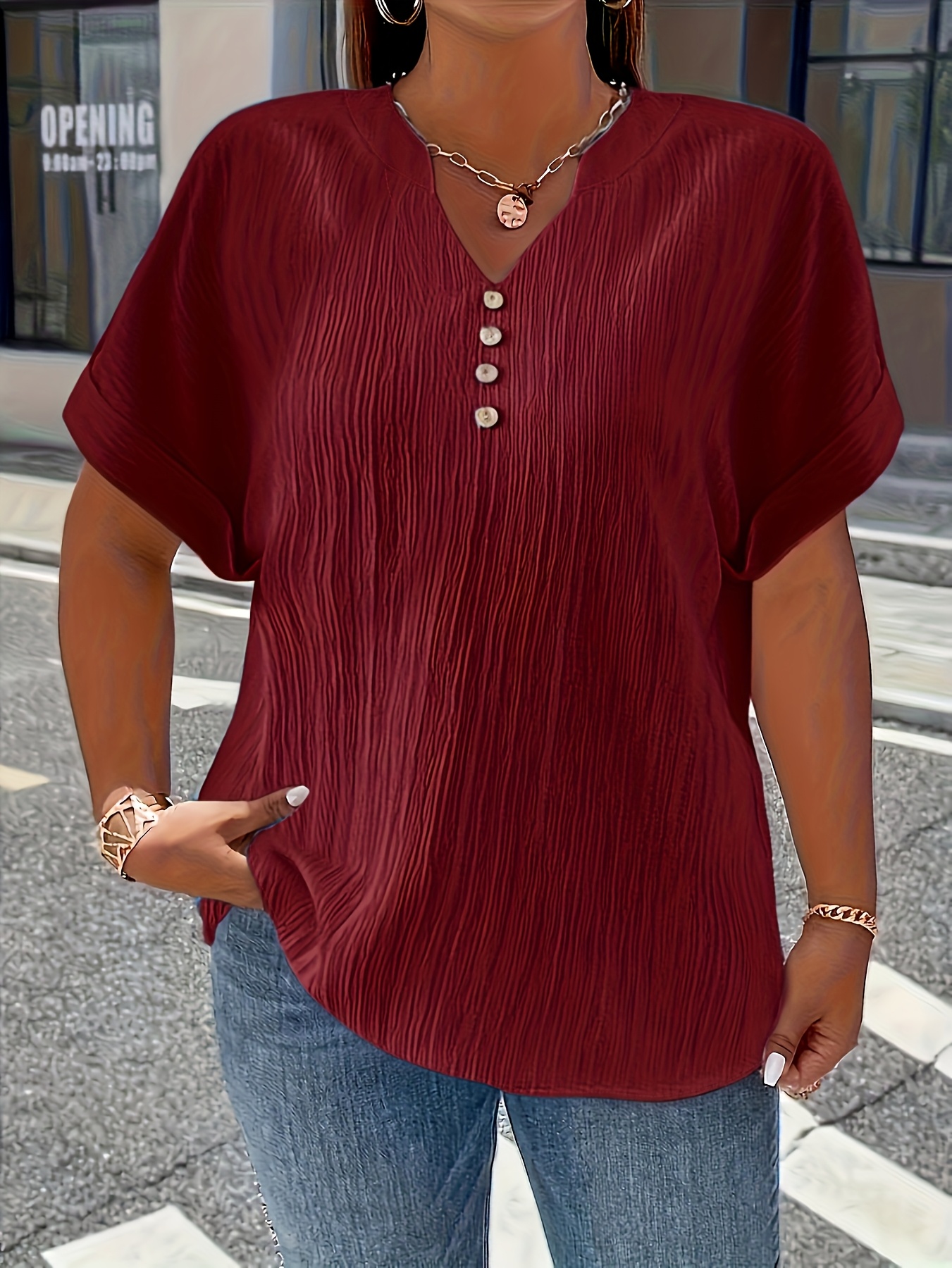 Damska bluzka plus size z efektem pogniecionej tkaniny, zapinana na guziki, o luźnym kroju, z krótkim rękawem.