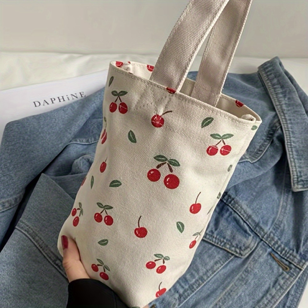 Esta linda bolsa tote com estampa floral de cereja é perfeita para uso diário e pode acomodar uma garrafa de água.