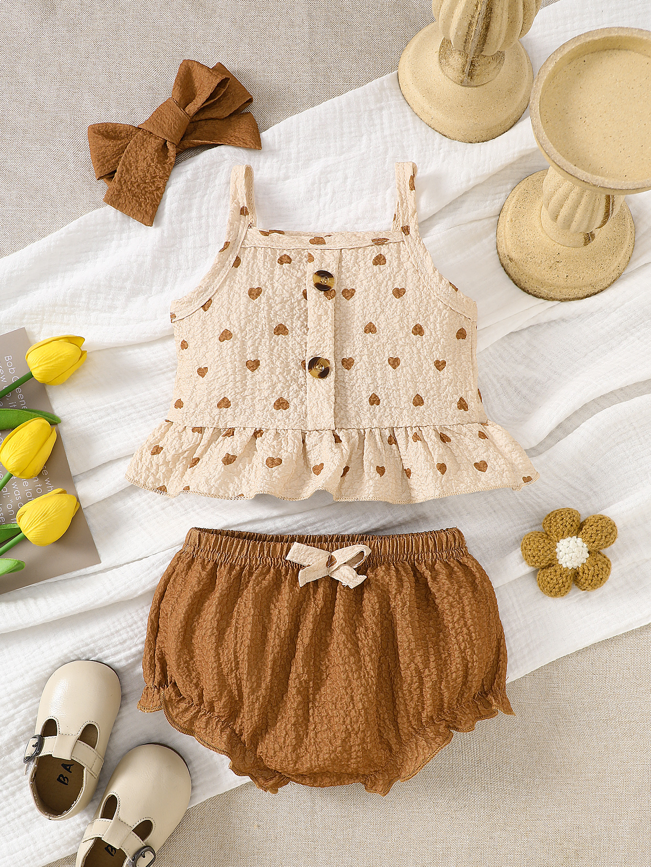 Zomerse abrikooskleurige top met hartjesprint en bretels voor een pasgeboren babymeisje, gecombineerd met een bruine short en hoofdband, gepersonaliseerd en eenvoudig.